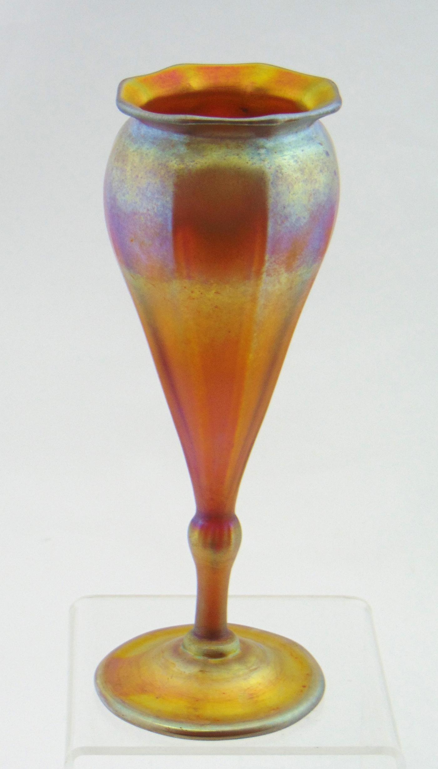 Tiffany gold Favrile glass vase,: Footed flower form vase with ribs and an everted scalloped rim signed 9896 D. L. C. Tiffany-Favrile, 7 1/2" ht. Condition: good with no defects found