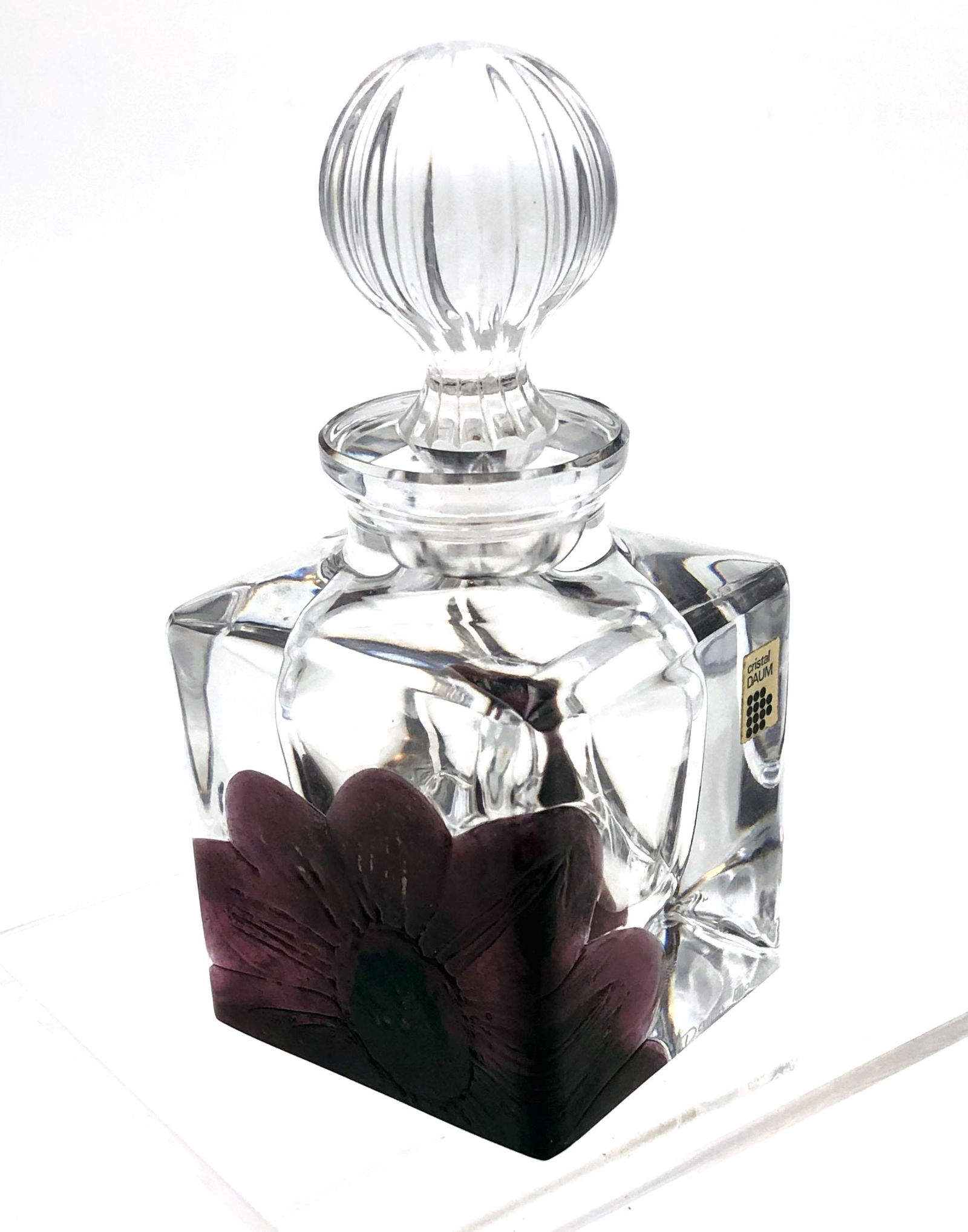 Daum Nancy crystal perfume bottle: Rectangular form in clear glass decorated with a purple marquetry flower, signed Daum France, 5 3/4" ht. Condition: chip of the underside of foot