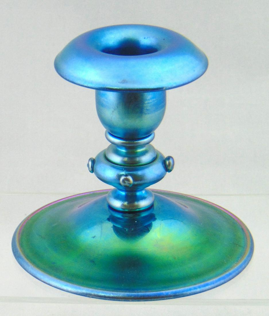 Steuben Blue Aurene glass candlestick: Low baluster form in Blue Aurene adorned with side prunts, signed Aurene 6384, 3 1/2" ht. Provenance: Rockwell Gallery to current owner. Condition: good with no defects found.