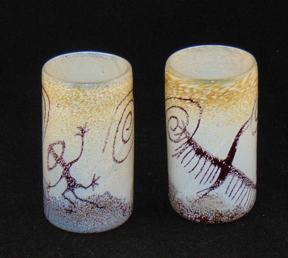 Pair of Rick Satava glass vases: Tumbler form in mottled white and yellow glass decorated with cave drawings, could be candle votives, one signed R Satava 04 and one with a paper label, 5 1/2" ht. Condition: good with no defects foun