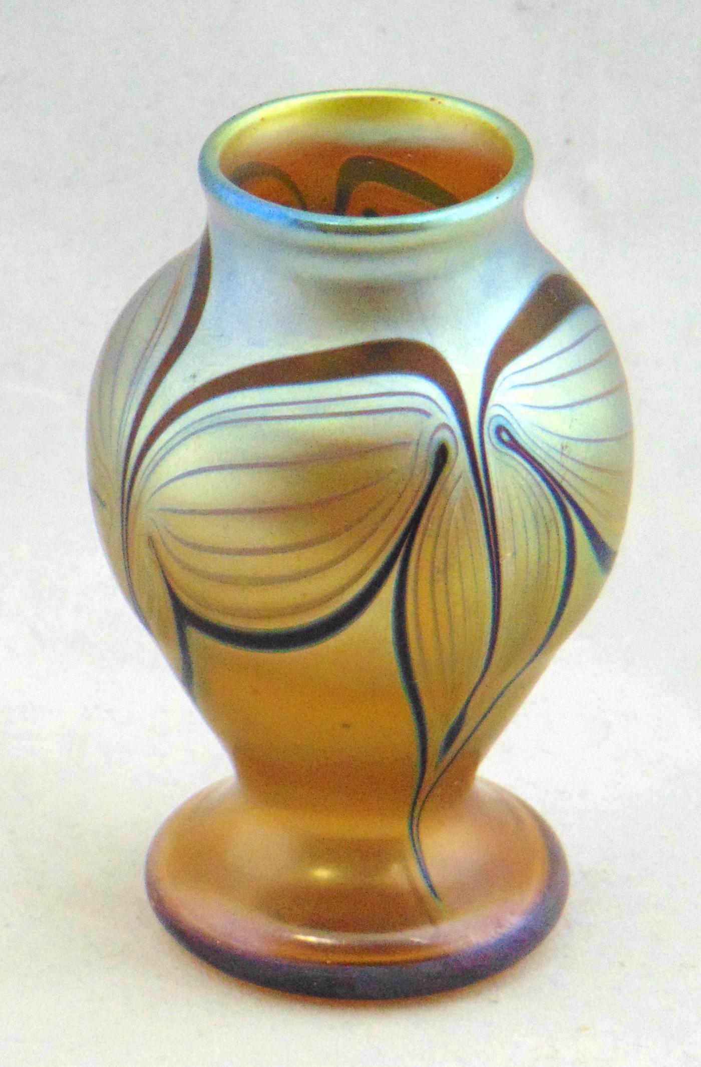 Orient and Flume art glass vase: Cabinet corset iridescent gold vase with a dark ruby pulled feather, signed Orient and Flume 1976, 3 3/4" ht. Condition: good with no defects found.