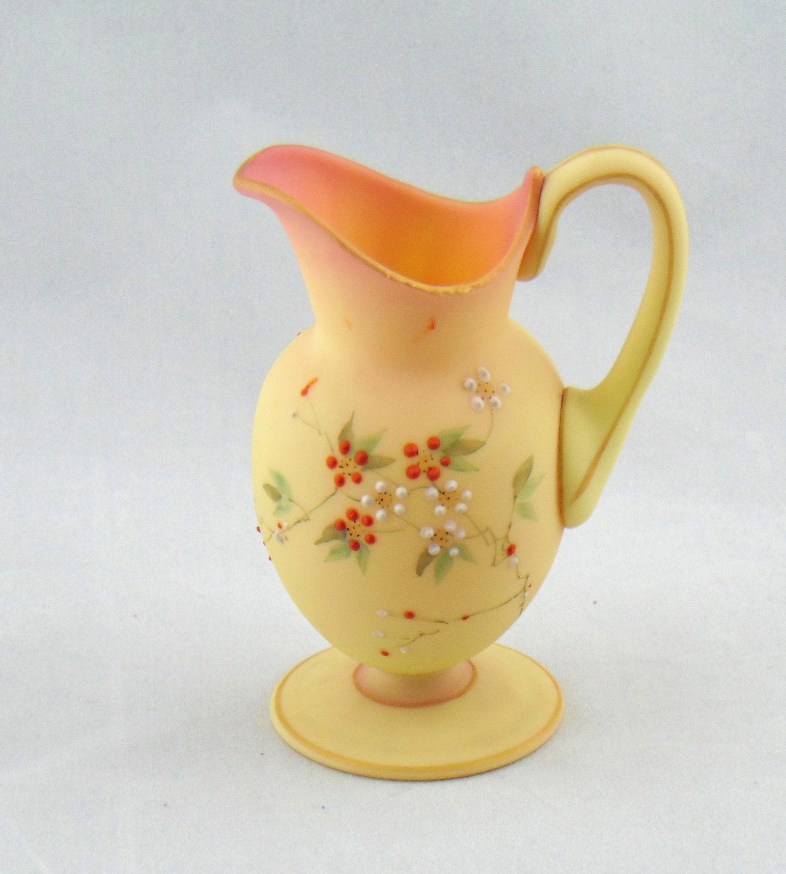 Mt. Washington Burmese creamer: Footed Burmese cream pitcher decorated with red and white daisies, 4" ht. Condition: good with no defects found.