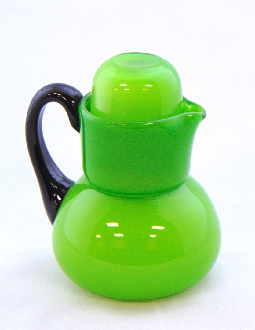 Loetz tango glass tumble up: Ovoid pitcher and internal tumbler in lime green glass with an applied black handle, 5 1/4" ht. Condition: good with no defects found.