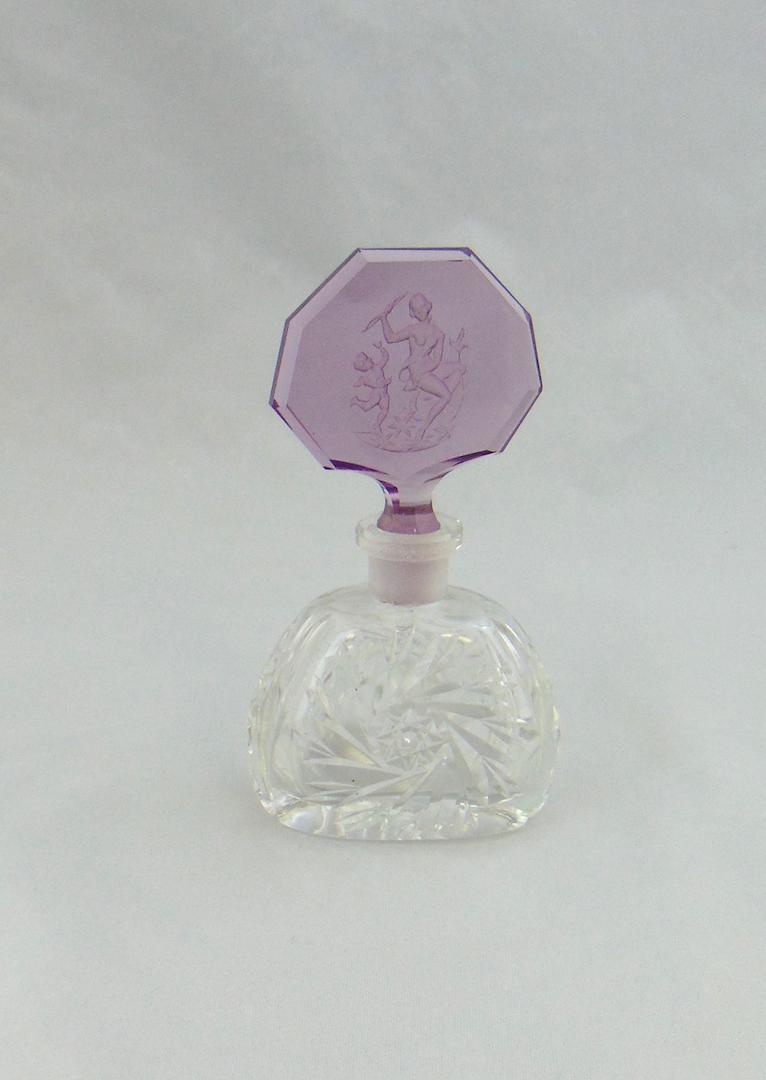 Czech clear glass perfume bottle: Clear perfume with a pinwheel design fitted with a faceted stopper with a Cupid and a Lady, 5' ht. Condition: good with no defects found.