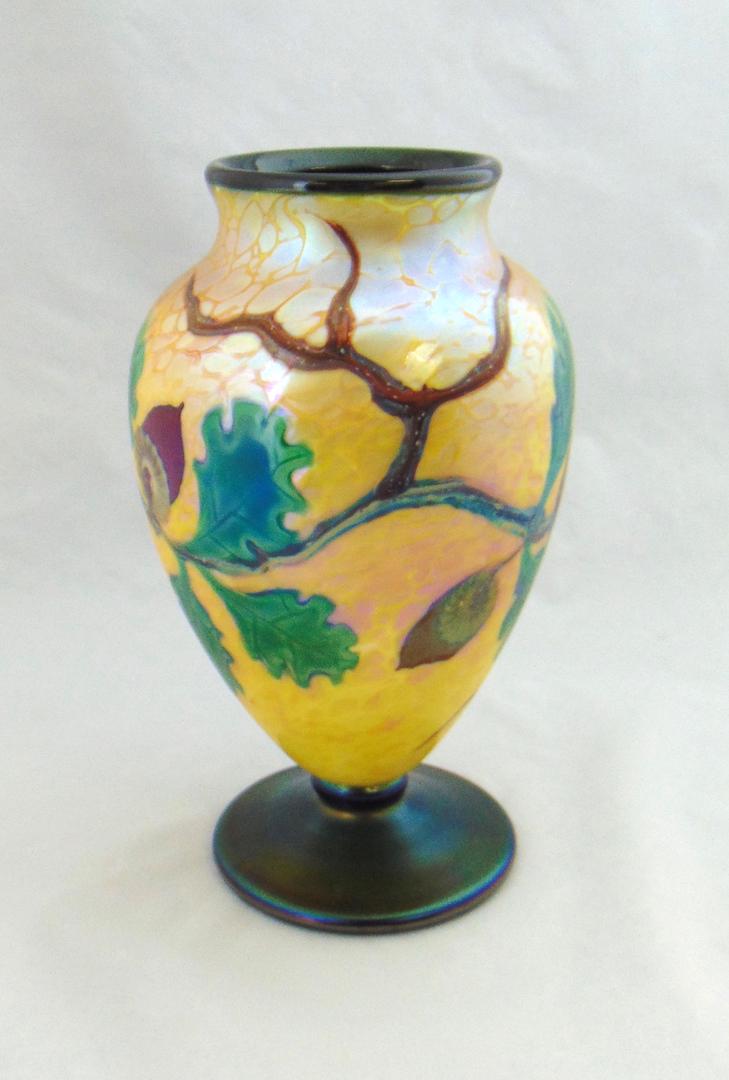 Orient and Flume art glass vase: Footed ovoid form in iridescent gold glass decorated with a oak branch with bright green leaves and six acorns, signed Orient and Flume Alexander/Smallhouse and carries a paper label, 9" ht. Condition