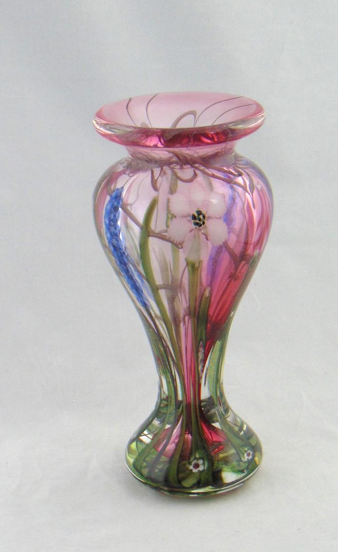 Vandermark paperweight glass vase: Corset form in translucent glass decorated with long stemmed blue, white and red flowers, signed Doug Merritt Stephen Smarr Vandermark, 10 1/4" ht. Condition: good with no defects found.
