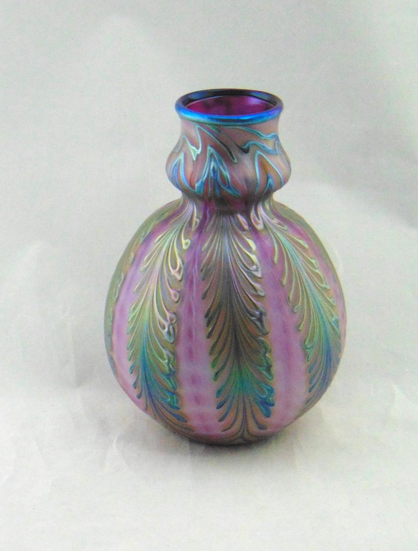 Charles Lotton Wisteria glass vase: Purple opaline bulbous bottle form decorated with cascading iridescent bluish green Wisteria, signed Charles Lotton 1994, 7 3/4" ht. Condition: good with no defects found.