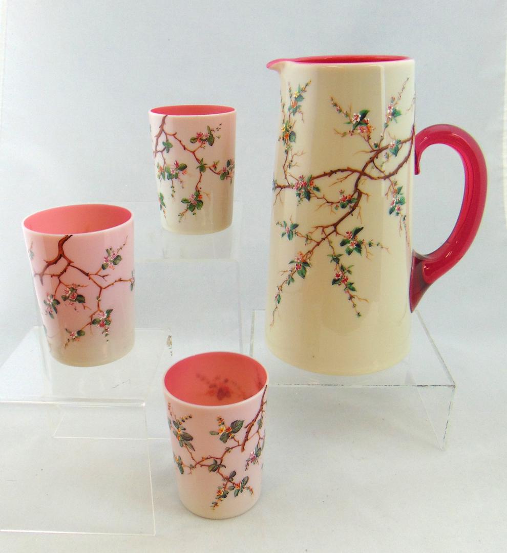 Opaline glass water set: Including a large opal tankard pitcher with pink interior and three matching tumblers, each decorated with enameled flowers, 9" ht. Condition: good with no defects found.