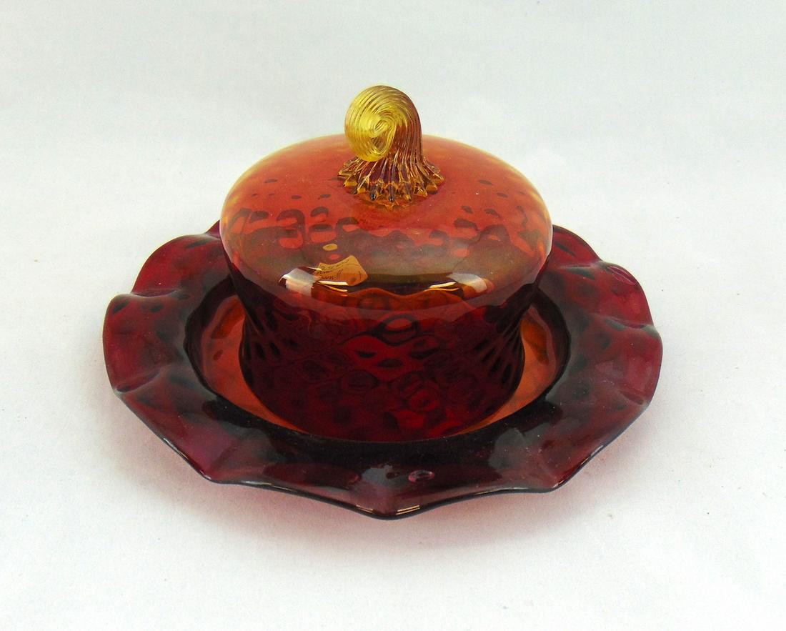 Amberina glass covered butter dish,: Dome shape covered dish in the optic diamond pattern set on an associated ruffled rim plate, 8" wide. PROVENANCE: Earlys Auction to the Black Collection. Condition: open bubble on the underplate.