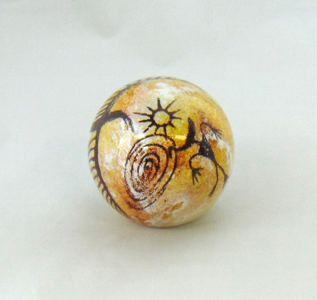Rick Satava glass Paperweight: Orb form Petroglyph paperweight in tan glass with cave drawings, signed R Satava 2978-94, 3" ht. Condition: good with no defects found.