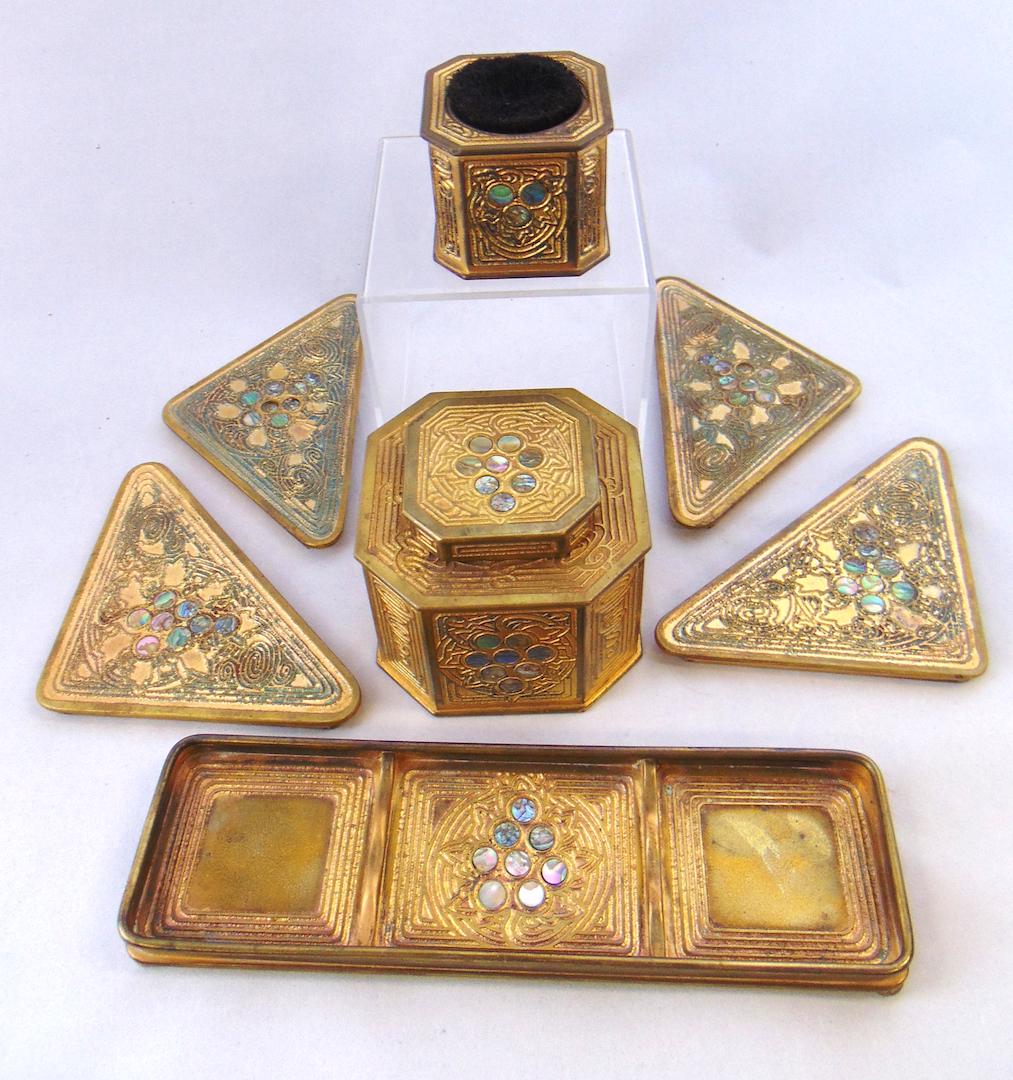Tiffany 7 piece Abalone desk set: Including four corner ends an ink well, pen tray, and a brush, each marked Tiffany New York, ink well 3" ht. Condition: seven jewels missing.