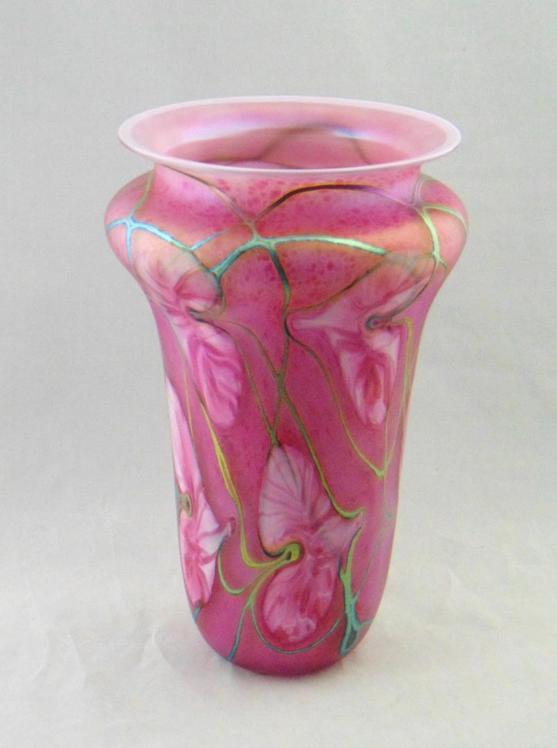 John Lotton pink art glass vase: Cylindrical shouldered form in mottled pink glass decorated with pointing pink hearts on iridescent gold vines, signed John Lotton 1995, 11" ht. Condition: good with no defects found.