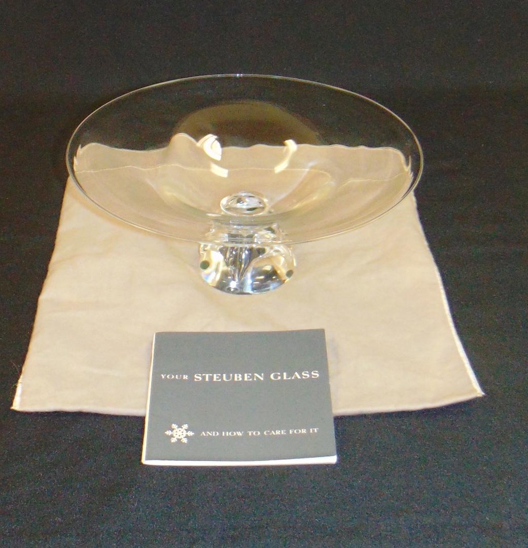 Steuben crystal glass compote: Rock form foot carries a spreading compote bowl, signed Steuben, has original gift bag and papers, 10 3/4" wide by 4" ht. Condition: good with no defects found