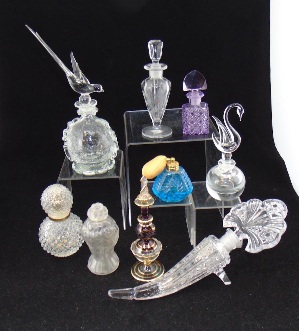 Group of 9 perfume bottles: Including two globular with bird finials a classic form with cut bird and flowers together with a Czech frosted Art Nouveau with ladies, a horn of plenty and more, tallest 9" ht. Condition: beak of on