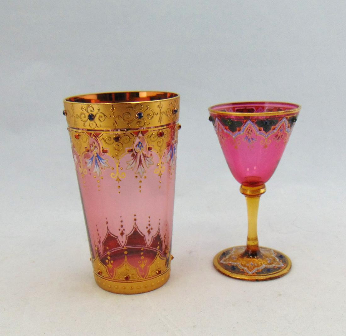 Two Moser glass items: Including a glass goblet and a tumbler both in cranberry and decorated with gilt panels and raised jewels, tallest 3 3/4" ht. Condition: good with no defects found.