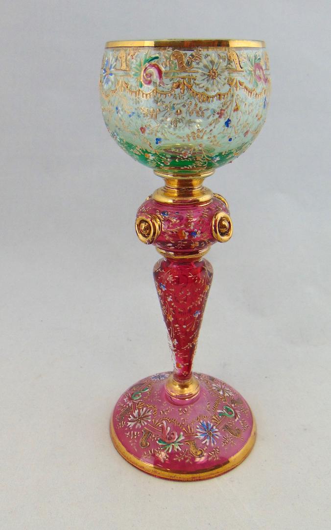 Fantastic Moser glass goblet: Cranberry foot and stem with side cabochons carry a green goblet with all over colorful flowers and gold scrolling, 7 1/2" ht. Condition: good with no defects found