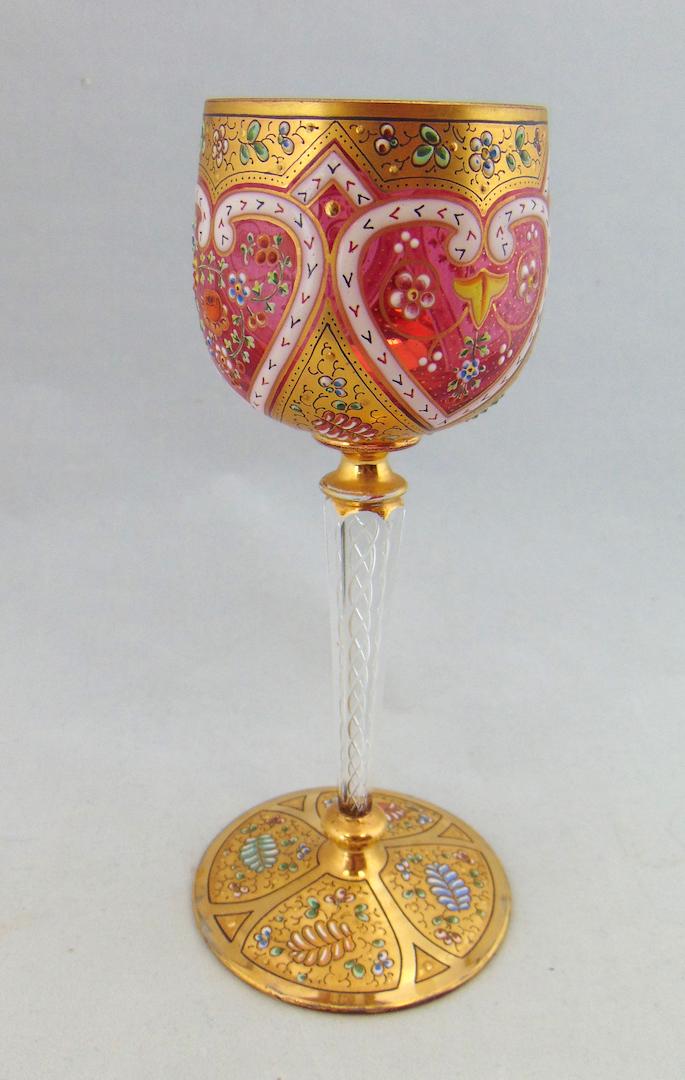 Magnificent Moser cranberry goblet: Cranberry goblet with swirled ribbon stem decorated with gilt panels of colorful flowers and heart shape medallion, 7 1/2" ht. LITERATURE: see "Moser Artistic Glass" book II by Baldwin page 87. Condit