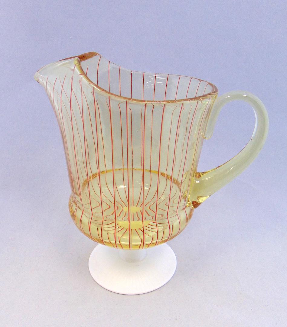 Fry/Pairpoint style water pitcher: Alabaster footed water pitcher in amber with red and white striated lines, 8 1/2' ht. Condition: good with no defects found.