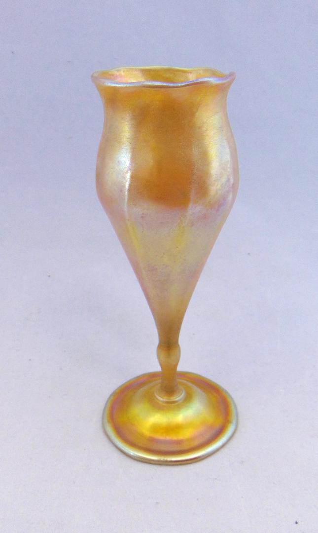 Tiffany gold Favrile flower form: Tiffany gold Favrile footed flower form with a ribbed body with a subtle undulating rim, signed L C Tiffany Favrile 4185G, 7" ht. Condition: good with great color, crimping tool mark on foot rim.