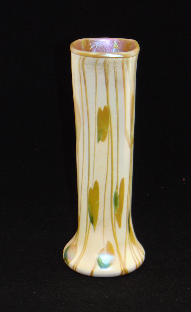 Rare Fostoria art glass vase: Cylindrical form in opal glass decorated with a group of cascading green and gold hearts on gold vines, 11" ht. Condition: good with no defects found.