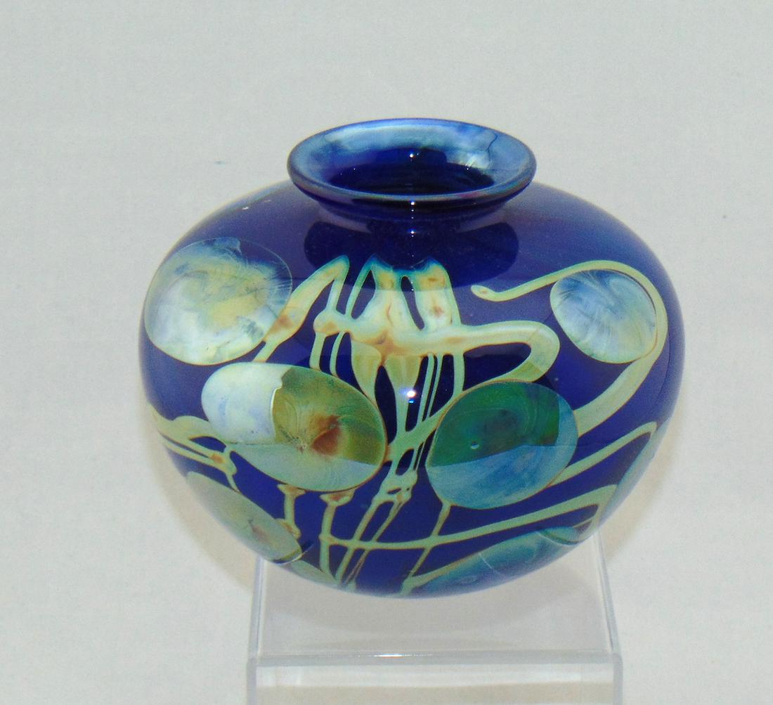 Dick Huss art glass orb: Blue shouldered form orb in dark blue with platinum and amber pods and vines, signed Dick Huss 77, 5 1/2" ht. Condition: good with no defects found.