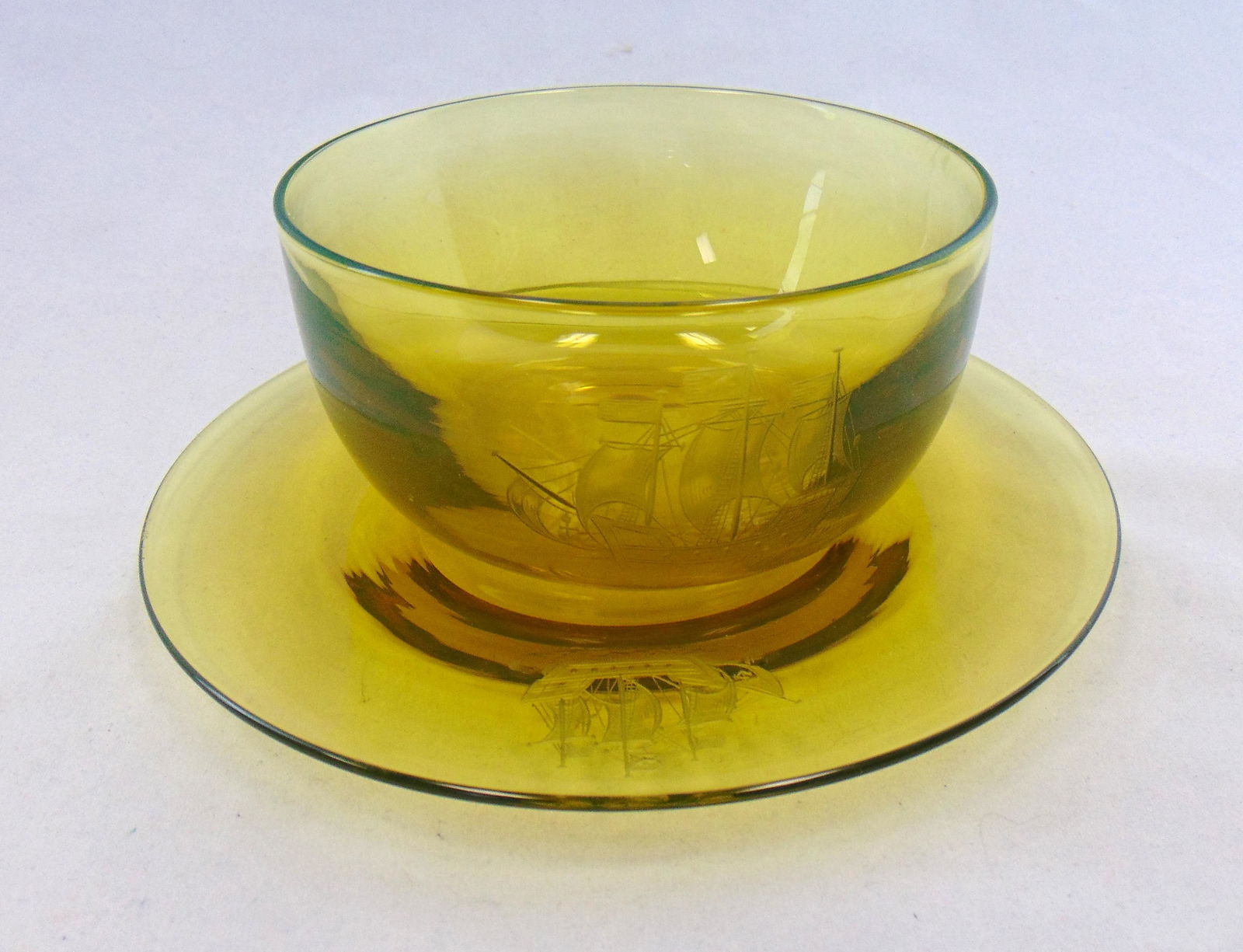 Steuben finger bowl and underplate: Steuben Vaseline finger bowl and underplate each etched with a sailing ship, 7 1/4" wide. Condition: good with no defects found.
