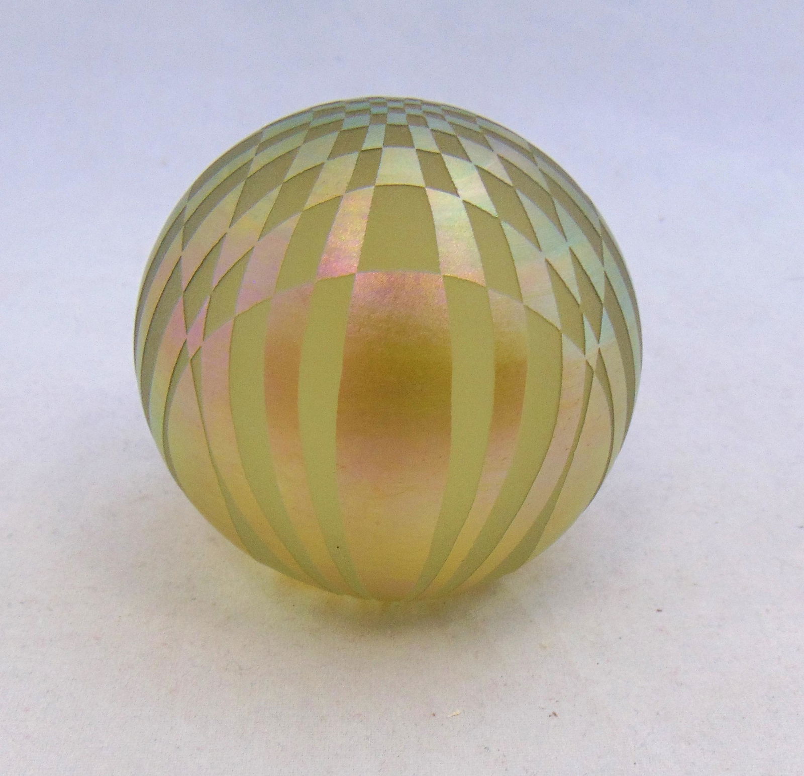 Barry Sautner glass paperweight: Ovoid paperweight in amber and iridescent gold cut in a geometric pattern, signed Vandermark Barry Sautner 3" ht. Condition: good with no defects found.