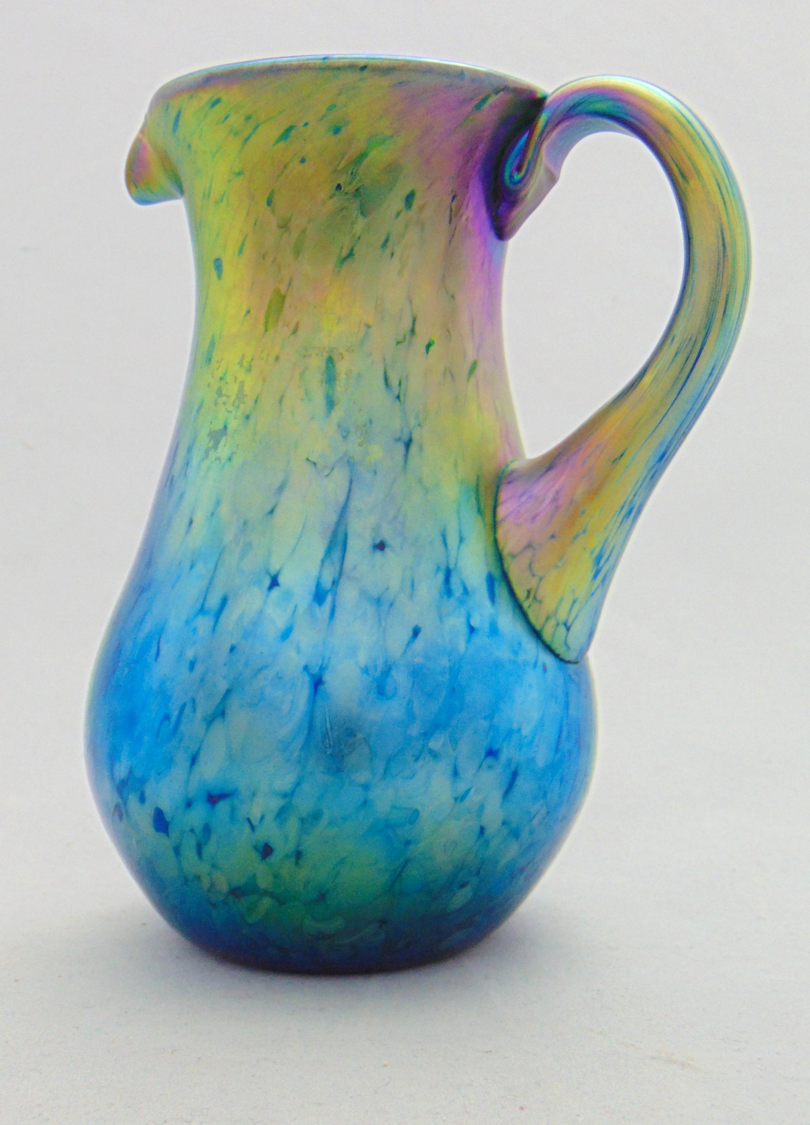 Lundberg iridescent glass pitcher: Blue iridescent Lundberg glass pitcher in the Sunset pattern, 5 1/2" ht. Condition: good with no defects found.