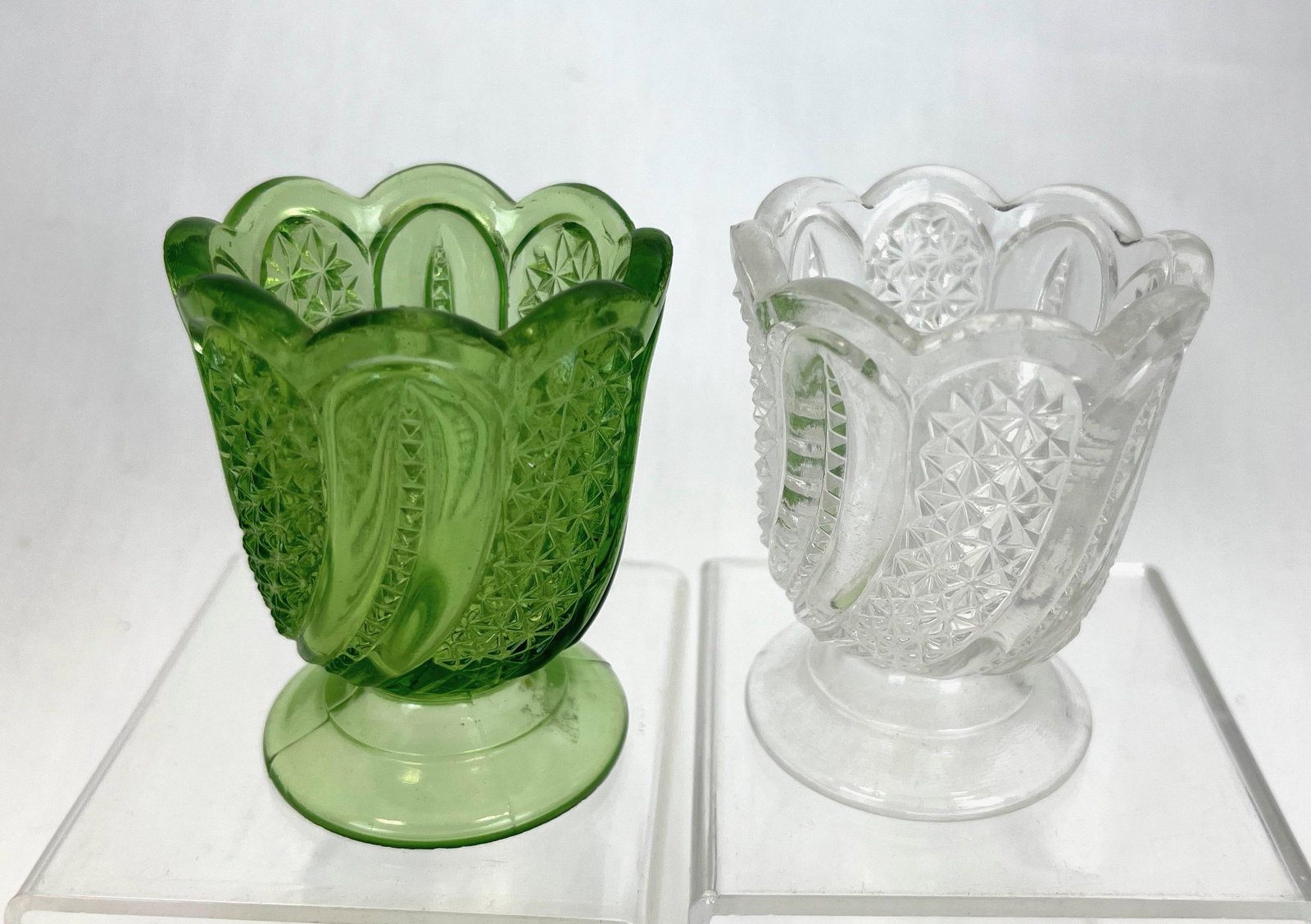 Two Feather toothpick holders: Two McKee & Bros Feather toothpick holders one clear and one emerald green; 2 3/4" ht. Literature: Bredehofts/the Sanfords - Glass Toothpick Holders, Second Edition, U.S. Glass Co p. 122. CONDITION: g