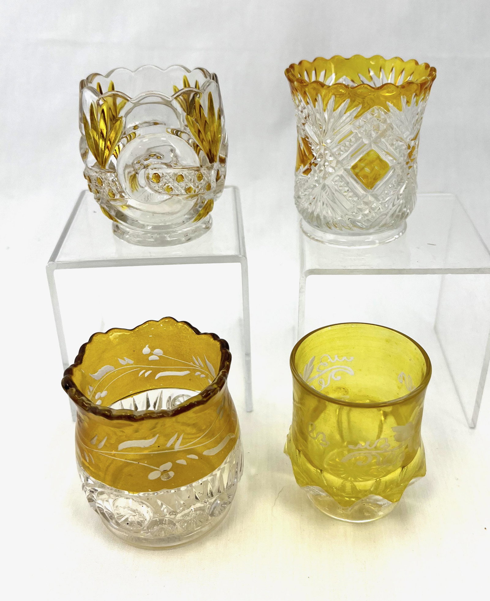 Four yellow stain EAPG toothpicks: Four yellow stain EAPG toothpick holders various makers and patterns including Zipper Slash, Esther, Scroll with Cane Band, and Tacoma; tallest 2.5". CONDITION: no defects noted.