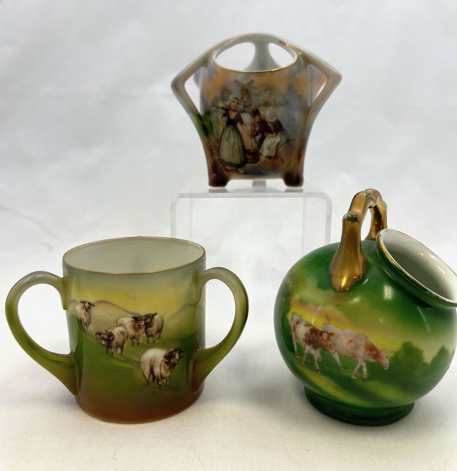 Three Royal Bayreuth toothpicks: Three Royal Bayreuth toothpick holders, one tri handled/opening Dutch scene, two with pastoral scenes one with cows, one with sheep; tallest 3". CONDITION: no defects found.