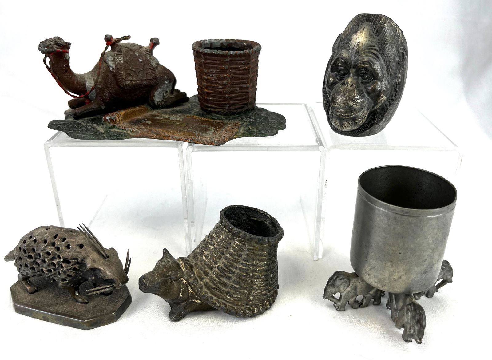 Five metal figural toothpick holders: Five metal figural toothpick holders including a camel, porcupine, monkey head, pig with a basket, and elephant foot; tallest 3". CONDITION: good with minor wear.