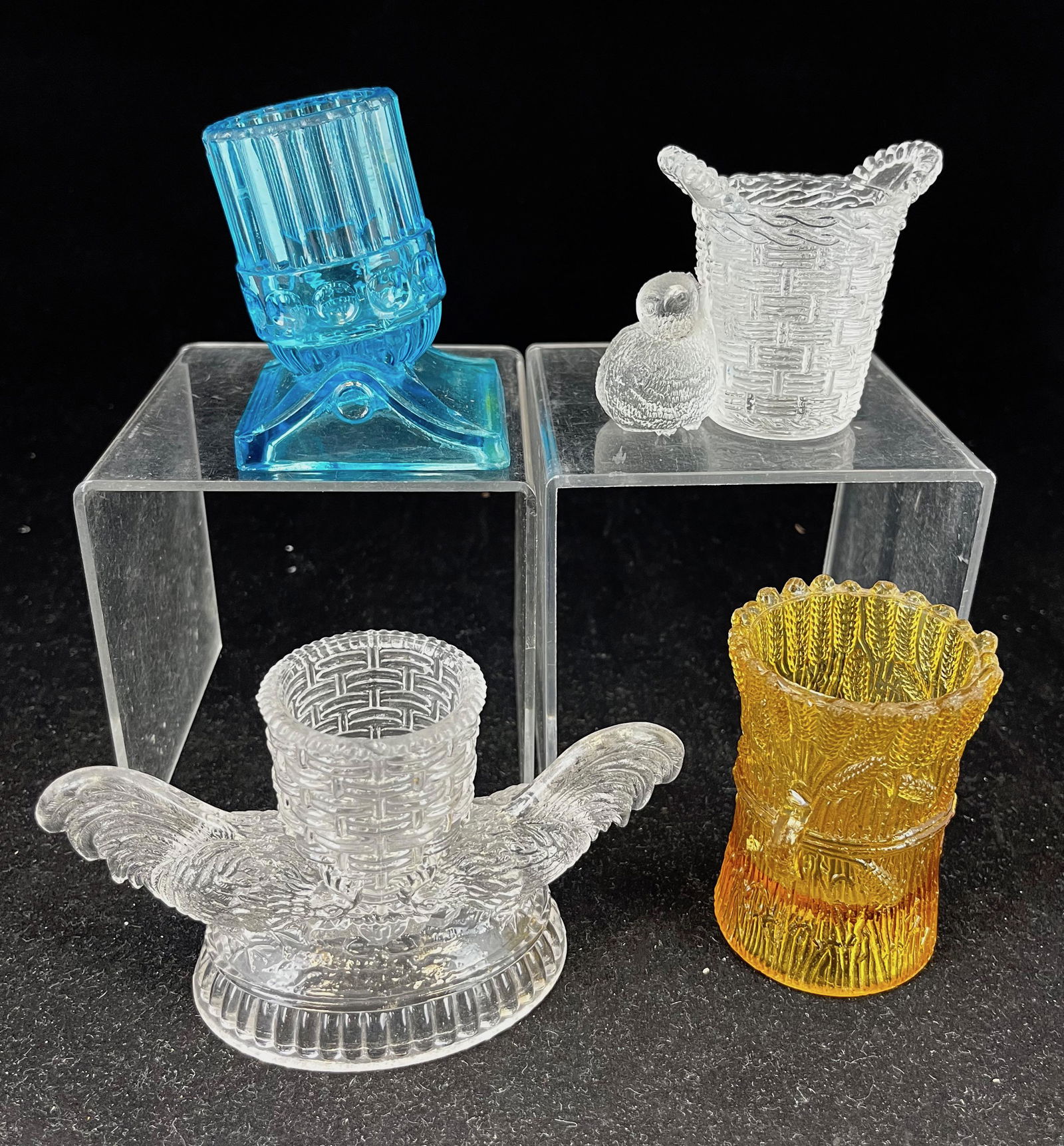 Four EAPG novelty toothpick holders: Four novelty toothpick holders various makers and patterns including a canary Sheaf of Wheat, clear Two Roosters, clear Bird with Basket, and blue Gatlin Gun; tallest 3". CONDITION: Gatlin Gun roughne