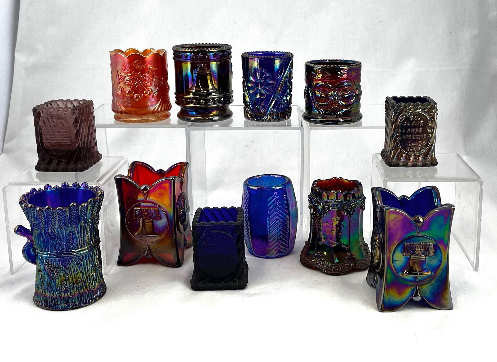 Group of 12 Carnival toothpicks: Group of 12 contemporary toothpick holders including 11 St. Clair patterns including a round ruby iridescent Indian, Geo. Washington, and Liberty Bell, a square amber and a blue iridescent Indian, Geo