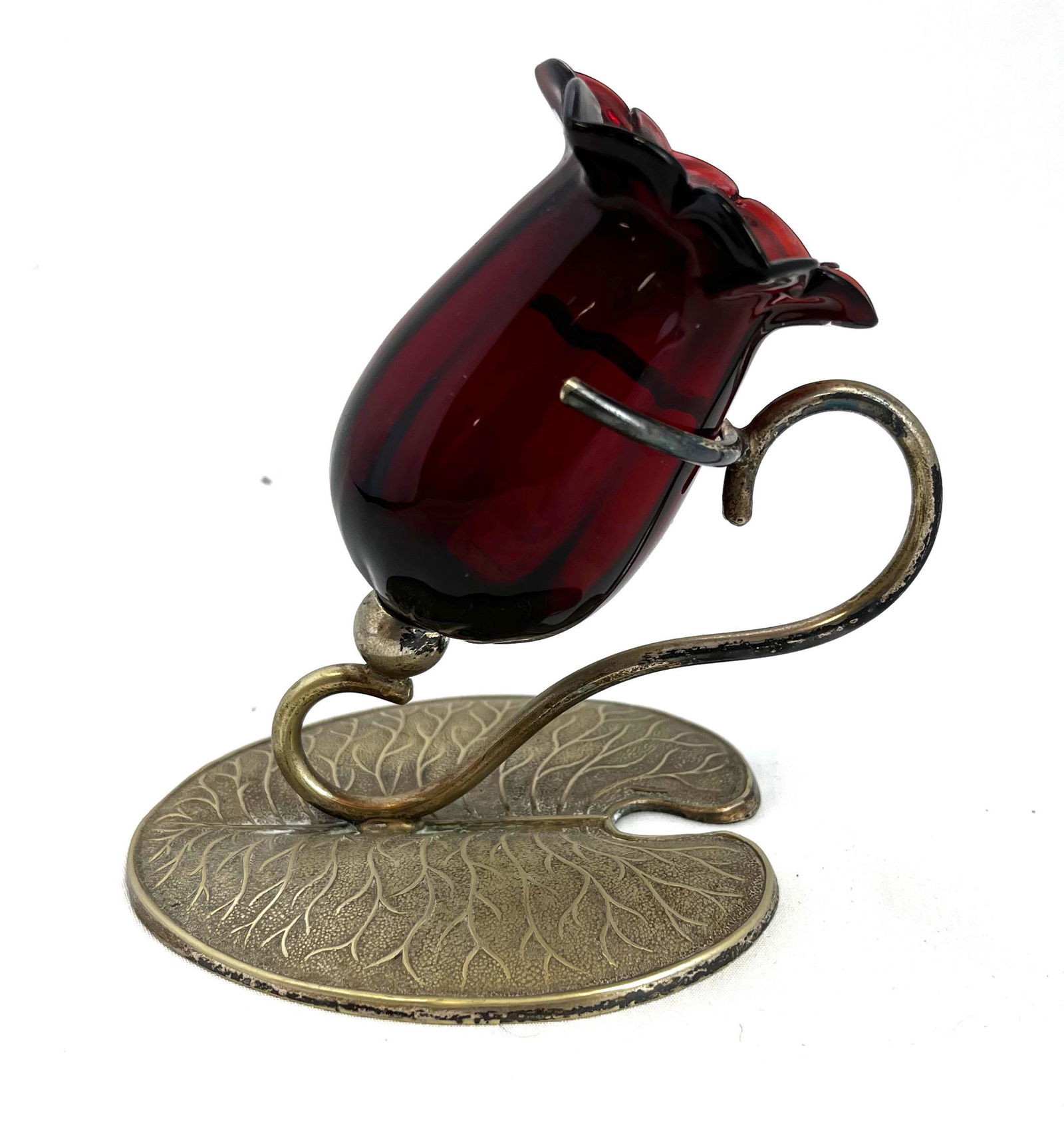 Ruby flower form, metal frame toothpick: Ruby ruffled top flower form toothpick set in a leaf base metal frame; 4 1/8" ht. Literature: Bredehofts/the Sanfords - Glass Toothpick Holders, Second Edition, p. 247. CONDITION: good with no defects