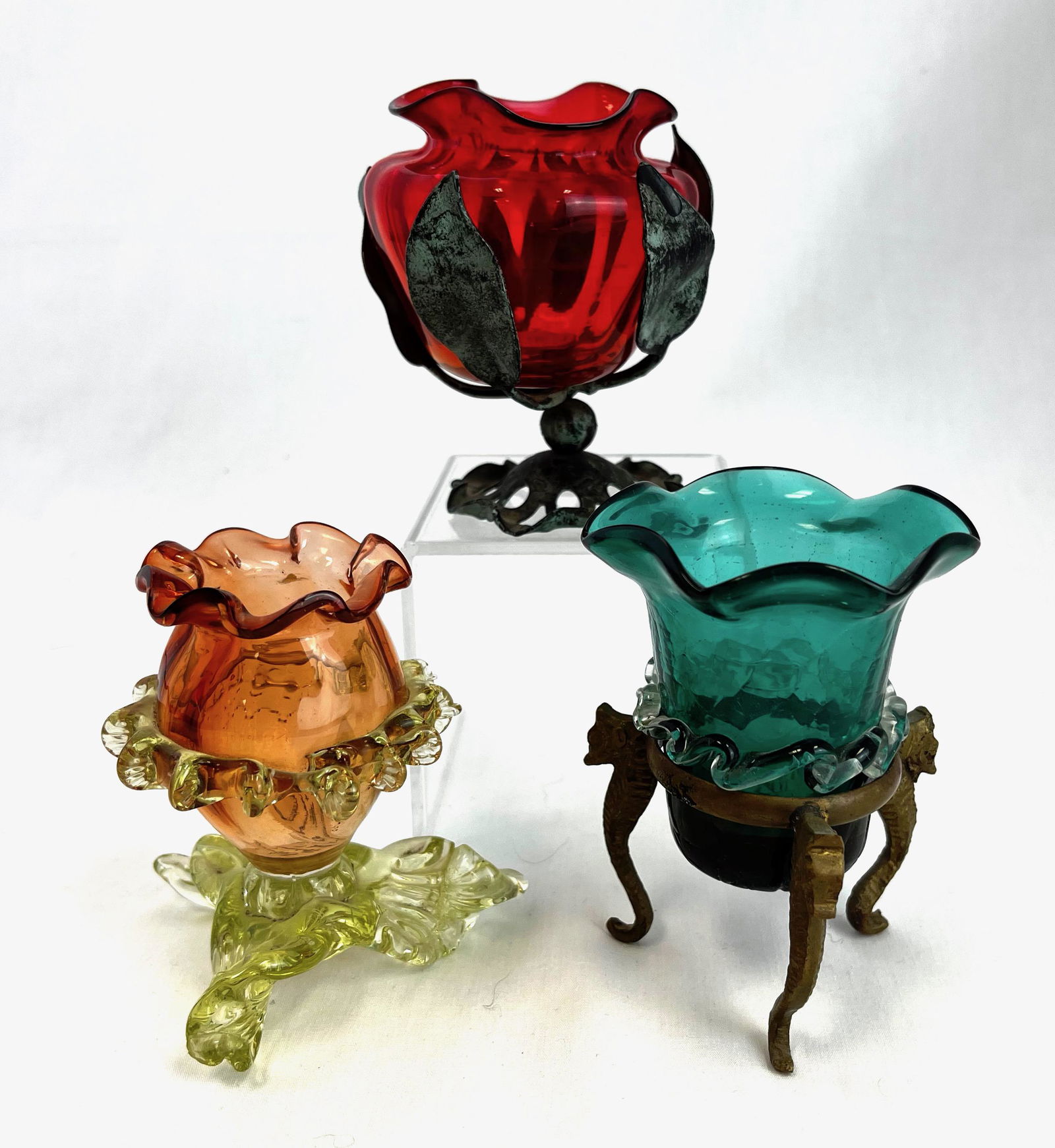 Three European toothpick holders: Three European toothpick holders including a Stevens & Williams peach with Vaseline rigaree, a blue with rigaree and metal frame, and an Amberina in a metal frame; tallest 3 3/4". CONDITION: chip to f