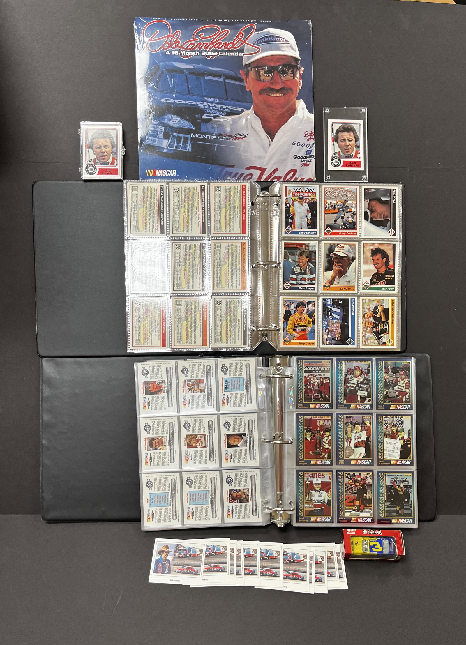 Group of Racing cards and more: 11 Richard Petty cards, Dale Earnhardt calendar and 1994 RCCA #3 toy car, 27 Alan Kulwicki cards, and two albums of cards approx. 620. Condition: good with no defects found, one Petty with staining.