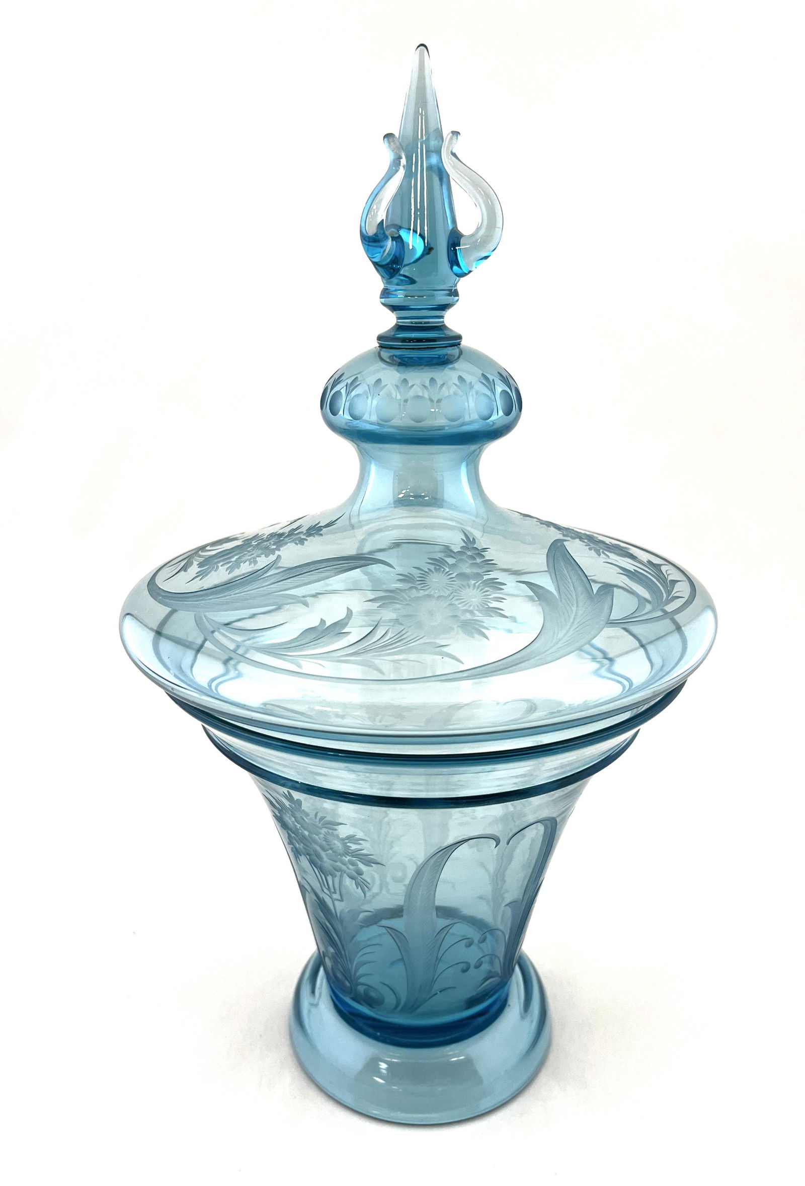 Steuben Celeste blue covered jar: Footed covered jar in Celeste Blue glass decorated with etched flowers and scrolling fitted with a crown finial lid, shape #6611, 13" ht. Condition: good with no defects found.