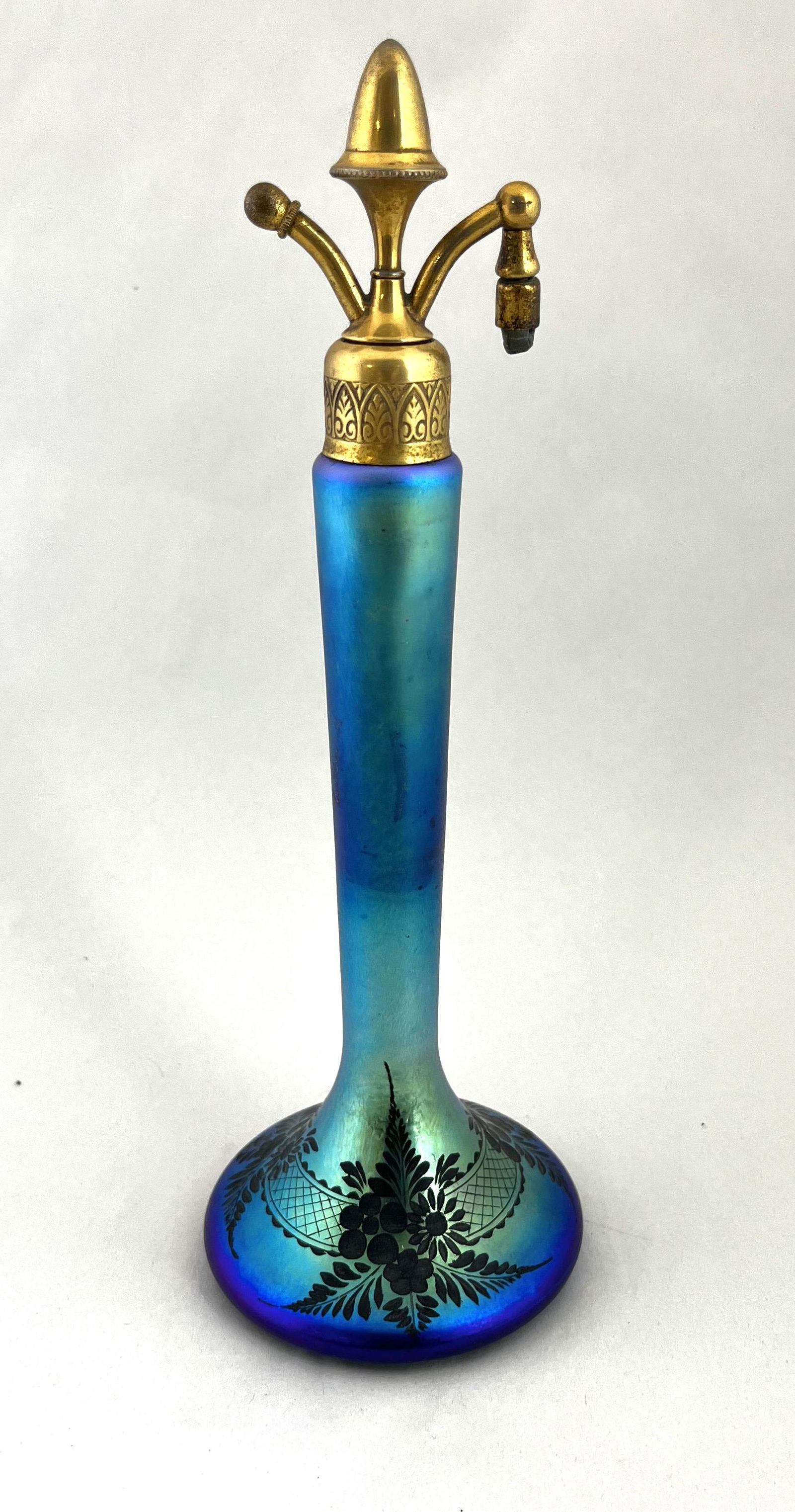Steuben Blue Aurene atomizer: Footed stick form in Steuben Blue Aurene decorated with intaglio cut flowers and lattice, signed in gold De Viblis, 9 1/2" ht. CONDITION: good with no defects found, no squeeze ball.