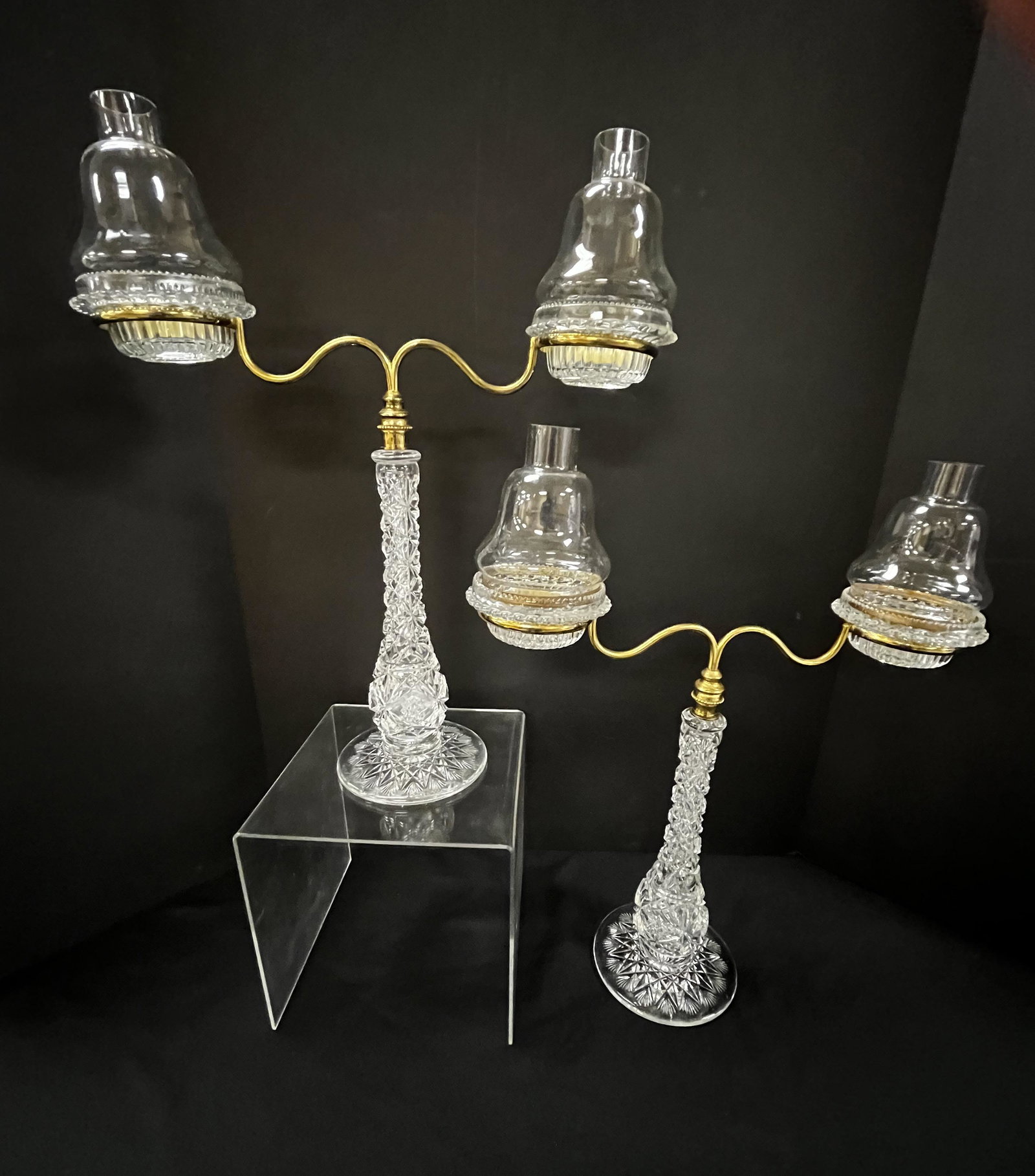 Pair of Cricklite two arm fairy lamps: Pair of Clarke two arm Cricklite pedestal fairy lamps with signed metal bands, cups and arms, 19" ht. LITERATURE: see "Fairy Lamps" by Ruf page 209. Condition: one cup with crack.