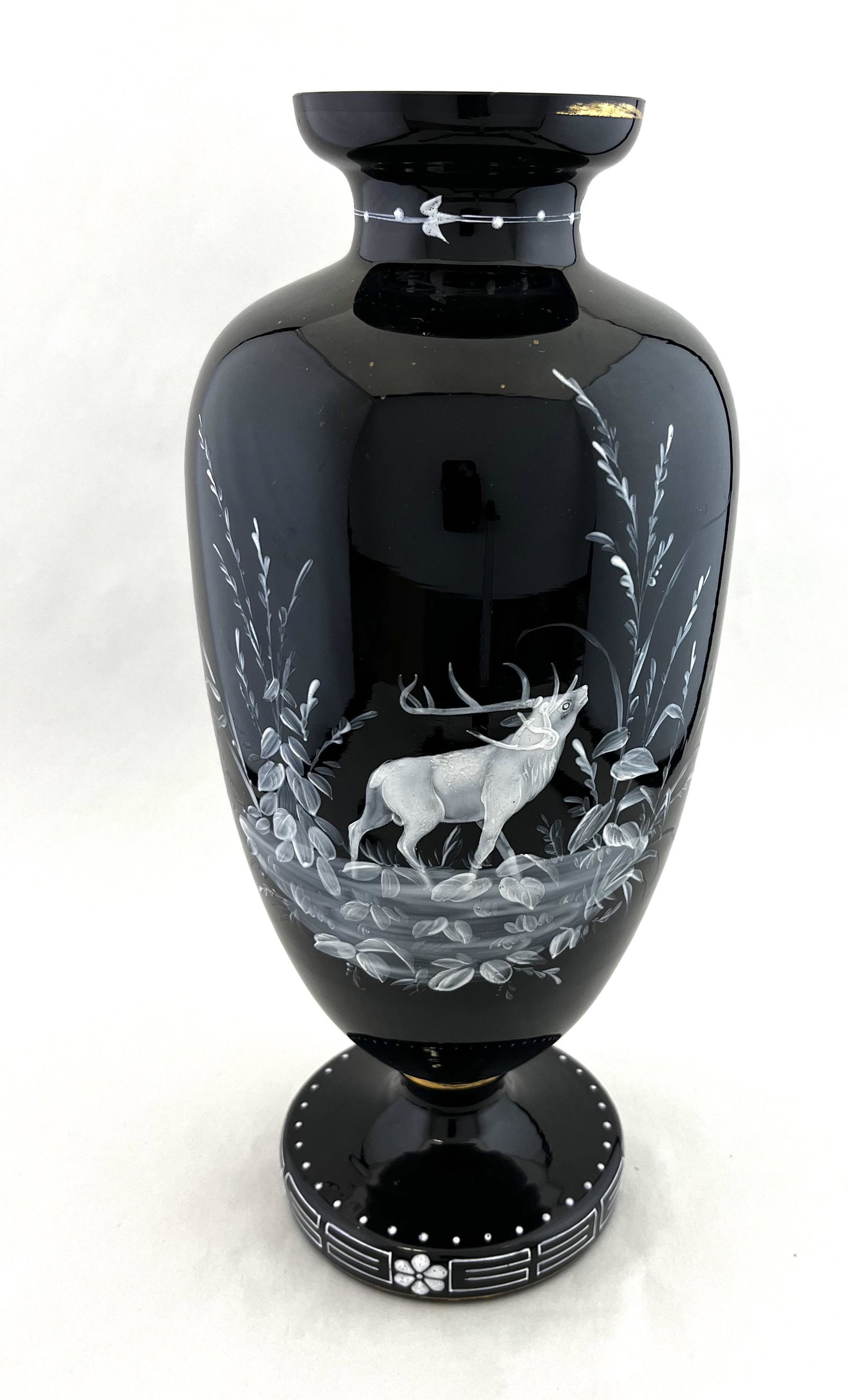 Black Opaline glass vase: Footed urn form black Opaline glass vase decorated with an enameled deer in the woods, 13" ht. CONDITION: good with no defects found.