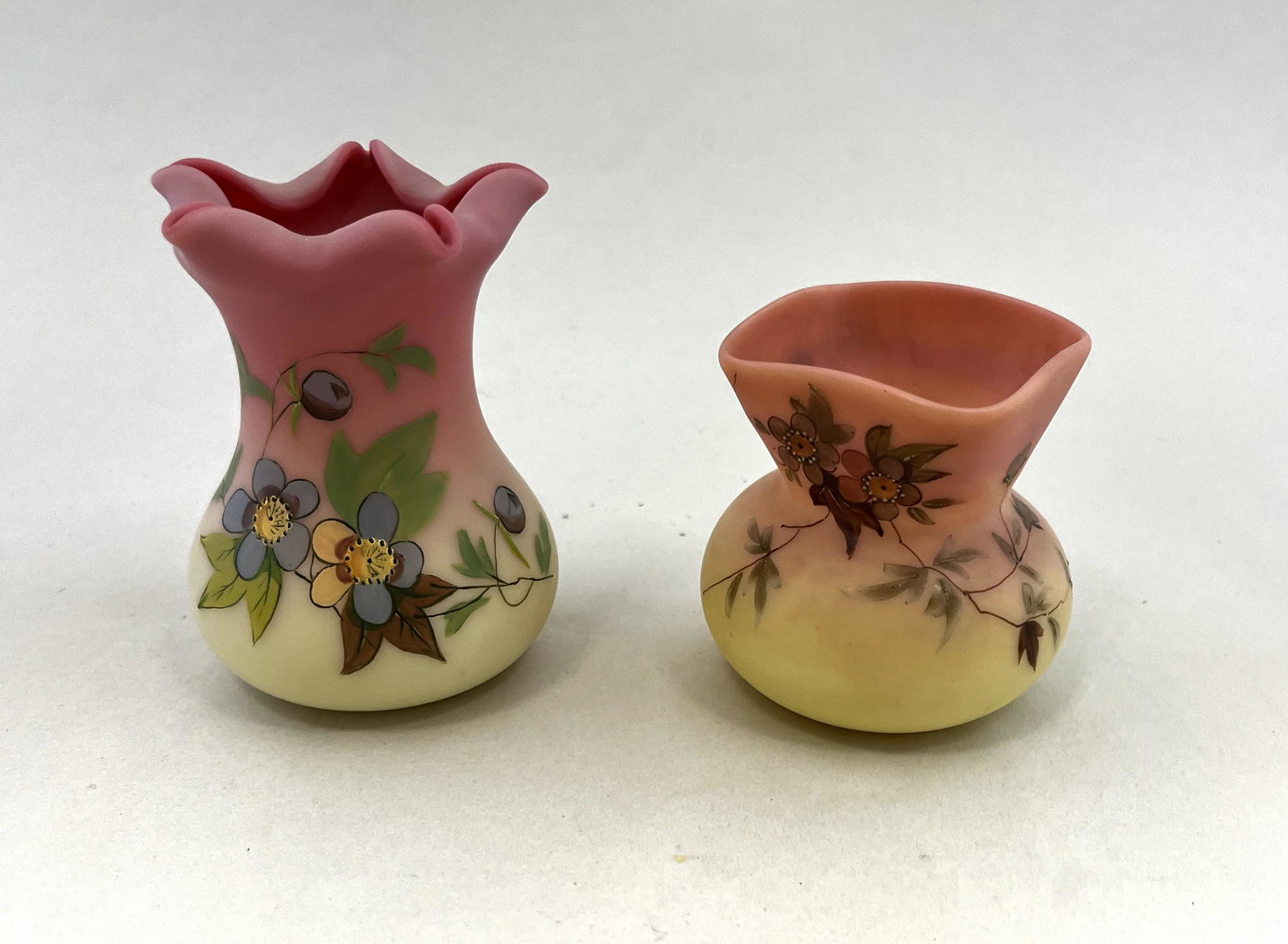 Two Webb Burmese glass items: Two decorated Webb Burmese glass vases including a toothpick in the Hawthorn pattern, together with a square mouth vase, tallest 3 1/4" ht. CONDITION: good with no defects found.