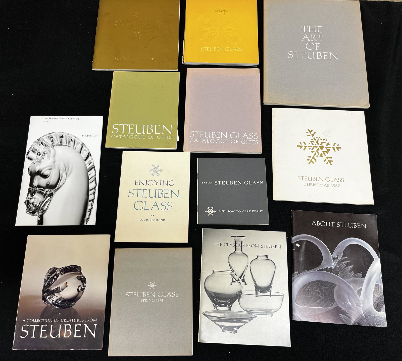 Books, 13 brochures of Steuben Glass: 13 brochures and catalogs of Steuben glass, including "The Art of Steuben" and catalogs from 1966, 1967, 1973, 1974, 1976, 1977, and 2003. CONDITION: wear commensurate with age