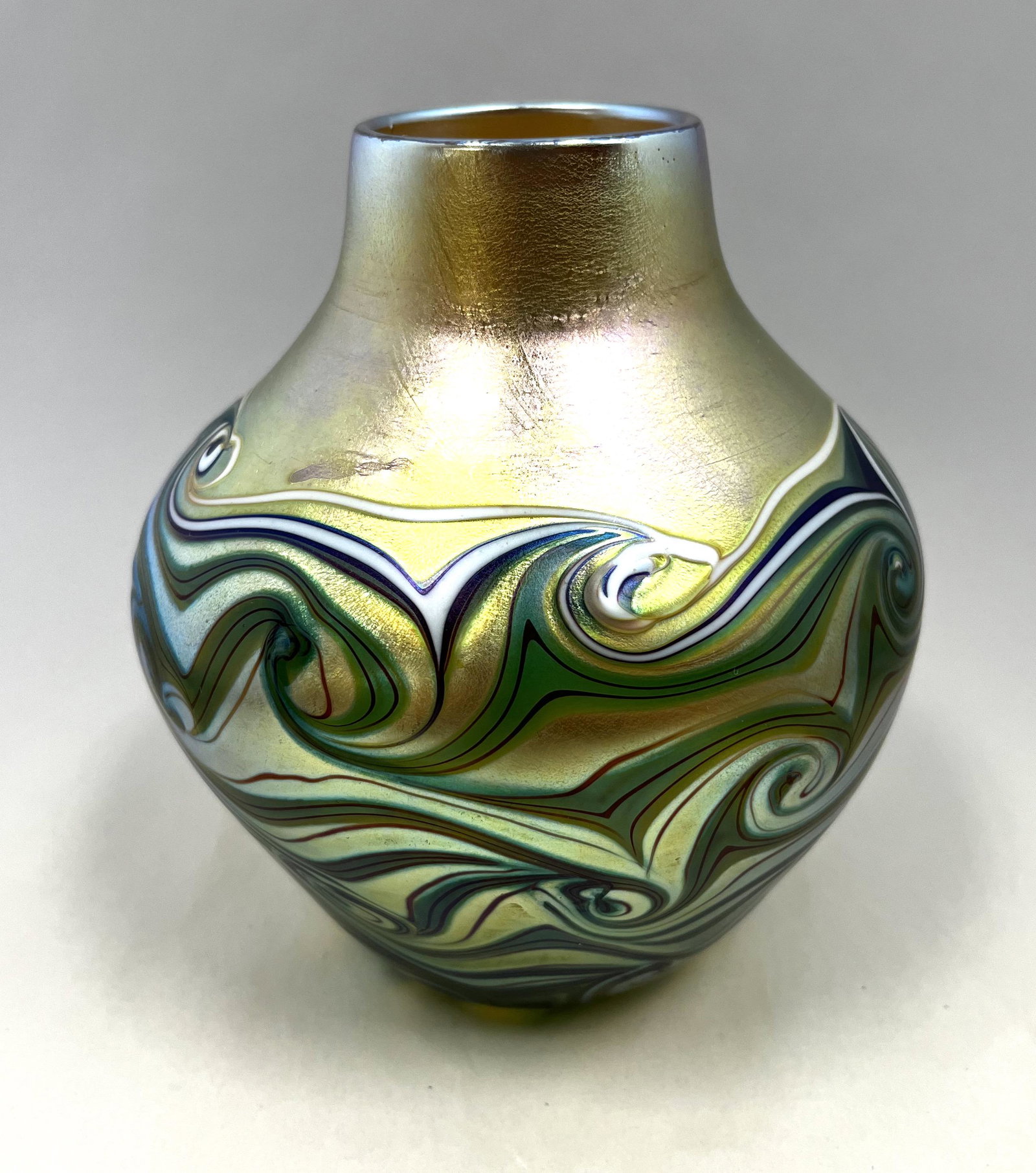 Orient and Flume art glass vase: Classic shouldered form in iridescent gold glass decorated with a blue and white hooked feather, signed Orient and Flume 1978, 6 1/2" ht. CONDITION: Good with no defects found