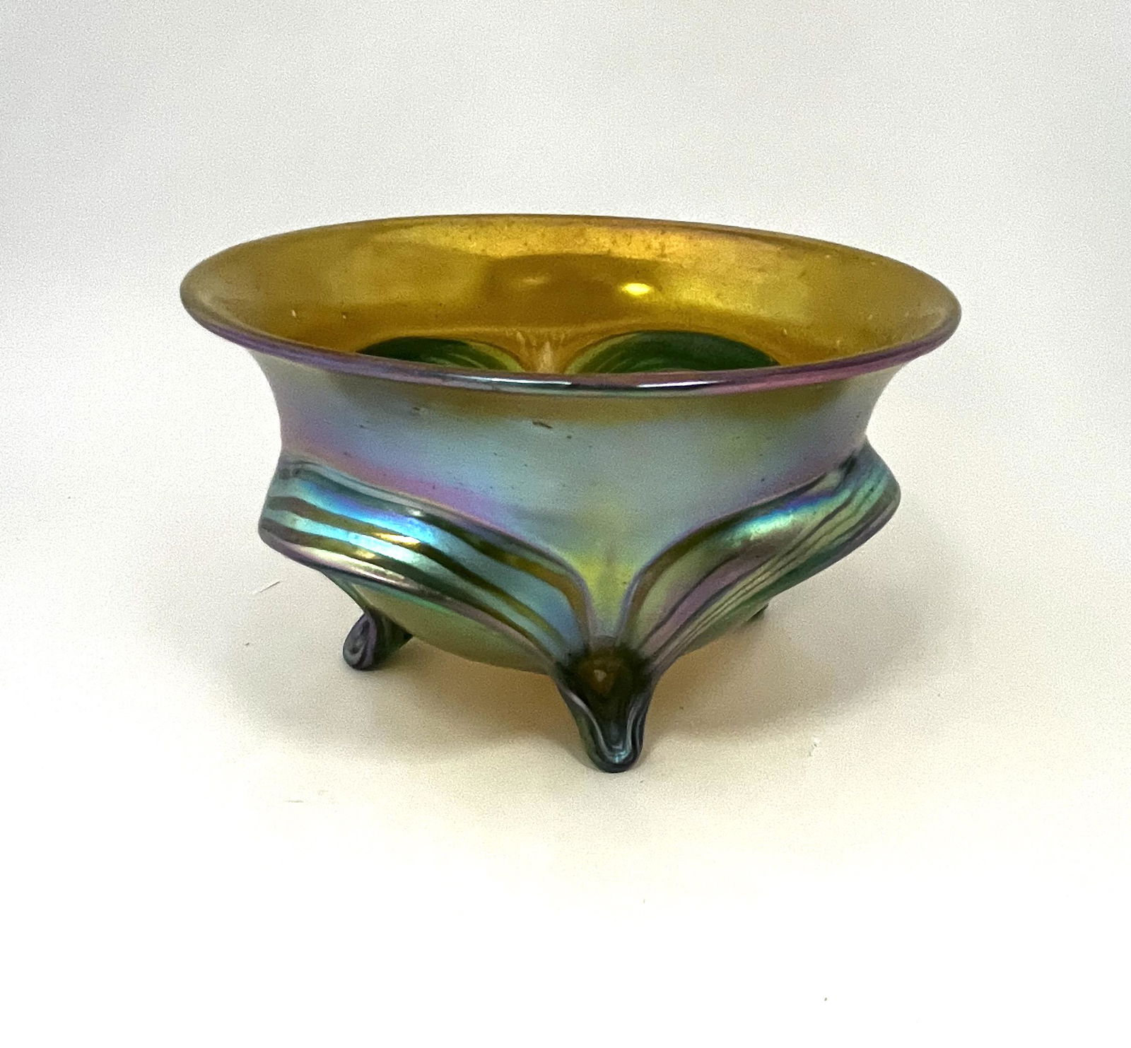 Bohemian art glass footed bowl: Iridescent amber glass bowl attributed to Loetz decorated with applied green feet, 4" ht. by 7" wide. CONDITION: Good with no defects found