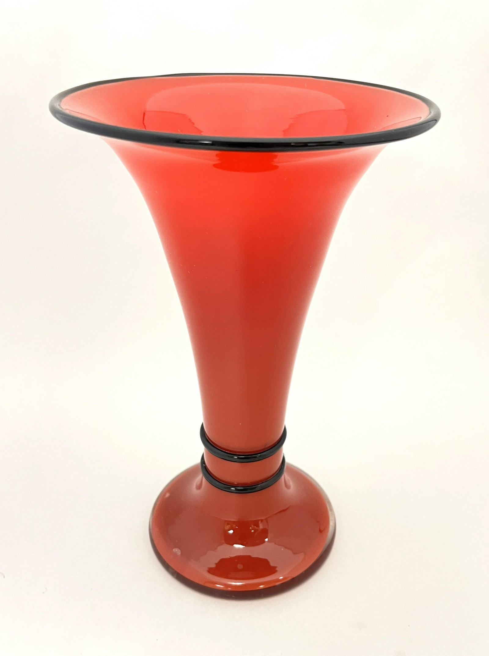 Red Tango art glass vase: Footed trumpet form Czecho glass vase in red tango glass decorated with a black lip wrap and waist, spurious Steuben signature, 9" ht. CONDITION: Good with no defects found