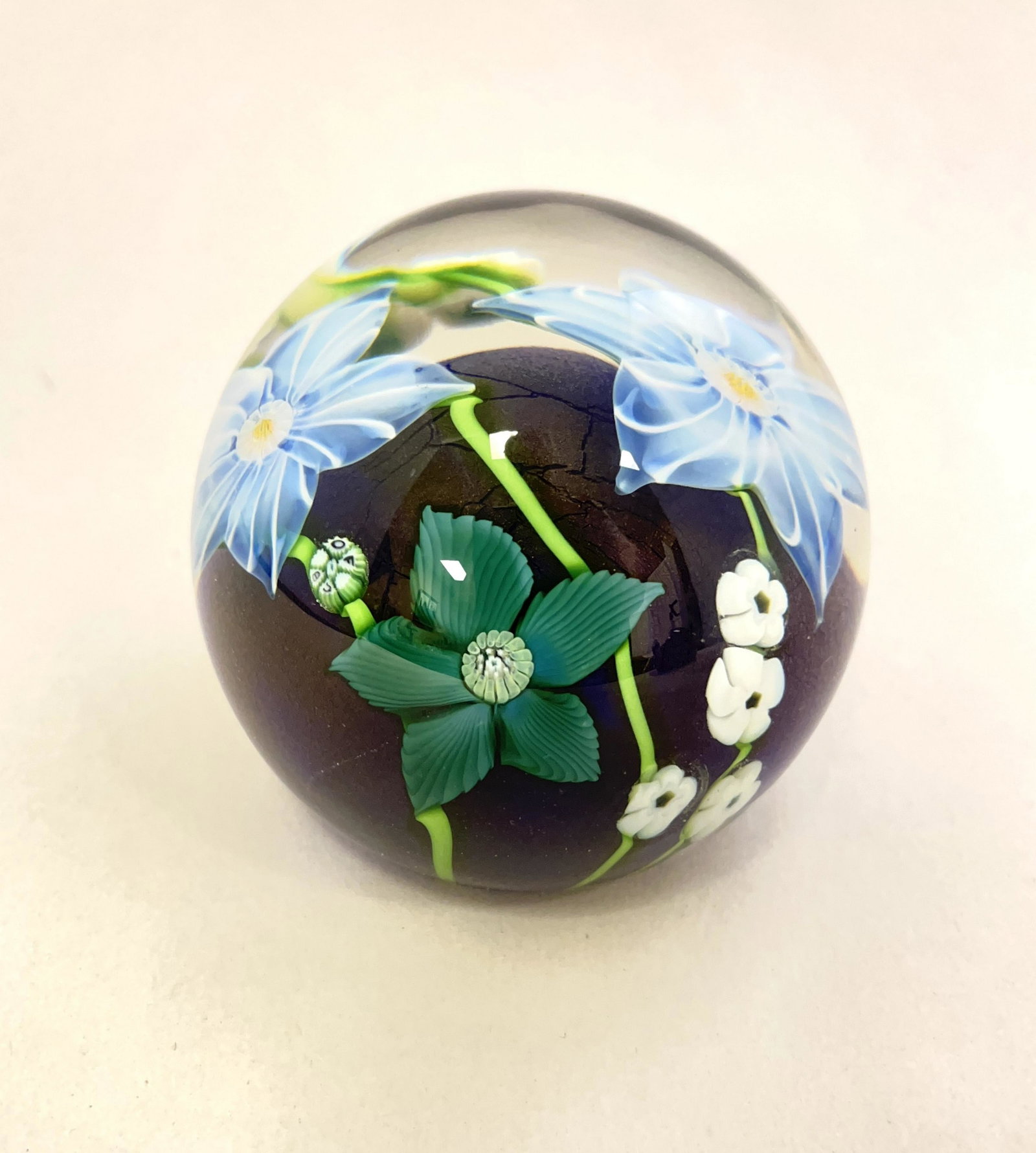 Orient and Flume paperweight: Orient and Flume blue paperweight with green white and blue flowers, signed Orient and Flume 1983, 3" wide. CONDITION: Good with no defects found