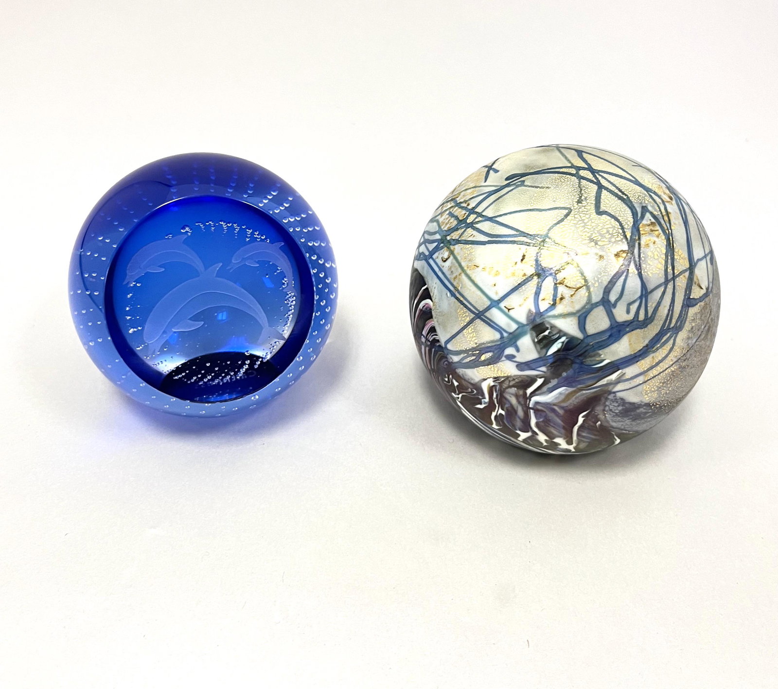 Two Scottish paperweights: Two Scottish paperweights including a blue signed Caithness with etched dolphins, together with a iridescent purple and white with blue trailings and gold aventurine with paper label Isle of Wright, l