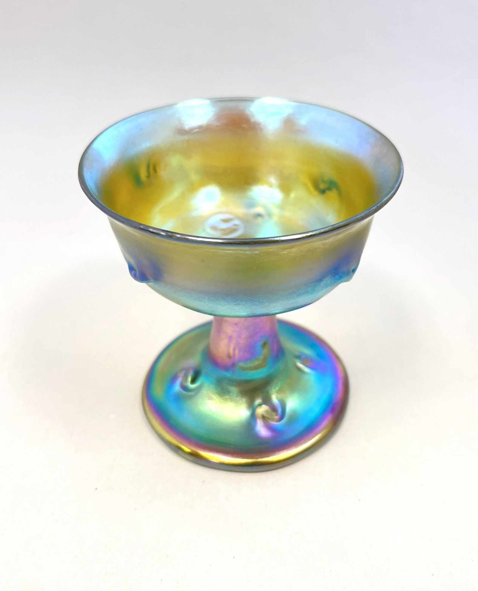 Tiffany gold Favrile sherbet: Tiffany gold Favrile sherbet with pig tail prunts, signed LCT; 3 1/2" ht. CONDITION: Manufacturing flaw interior, see picture. Jaremos attempts to call any material flaw that affects the price but min