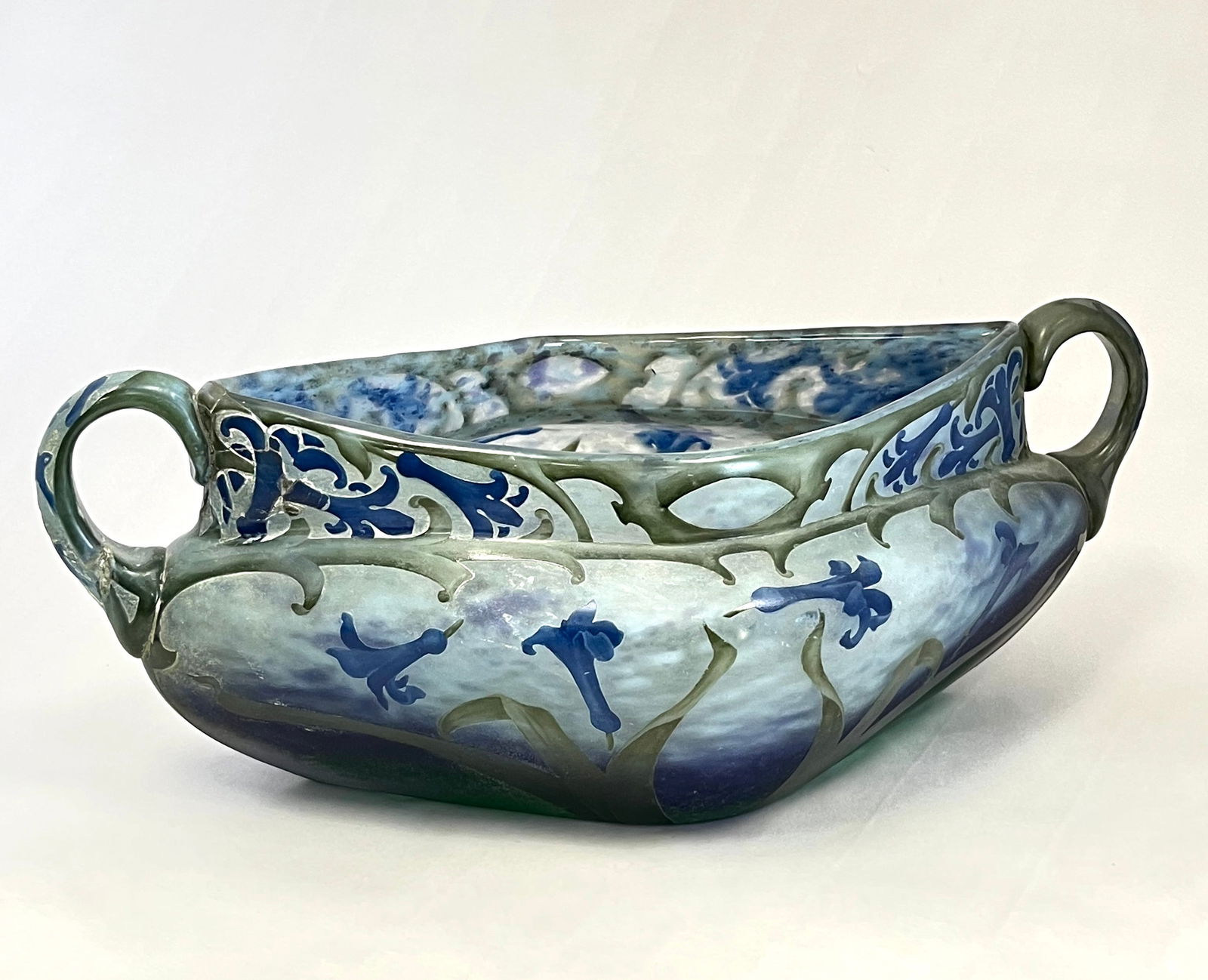 Daum Nancy French cameo glass bowl: Large Daum Nancy French cameo glass triangular bowl in mottled blue to purple decorated with blue flower on green stems an adorn with two side handles, signed in gold Daum Nancy, 13" long. CONDITION: